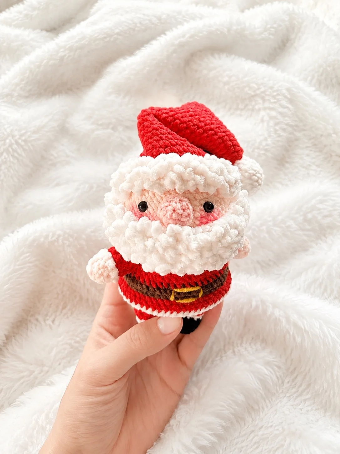 Handheld crochet Father Christmas with a red hat, fluffy white beard and brown belt